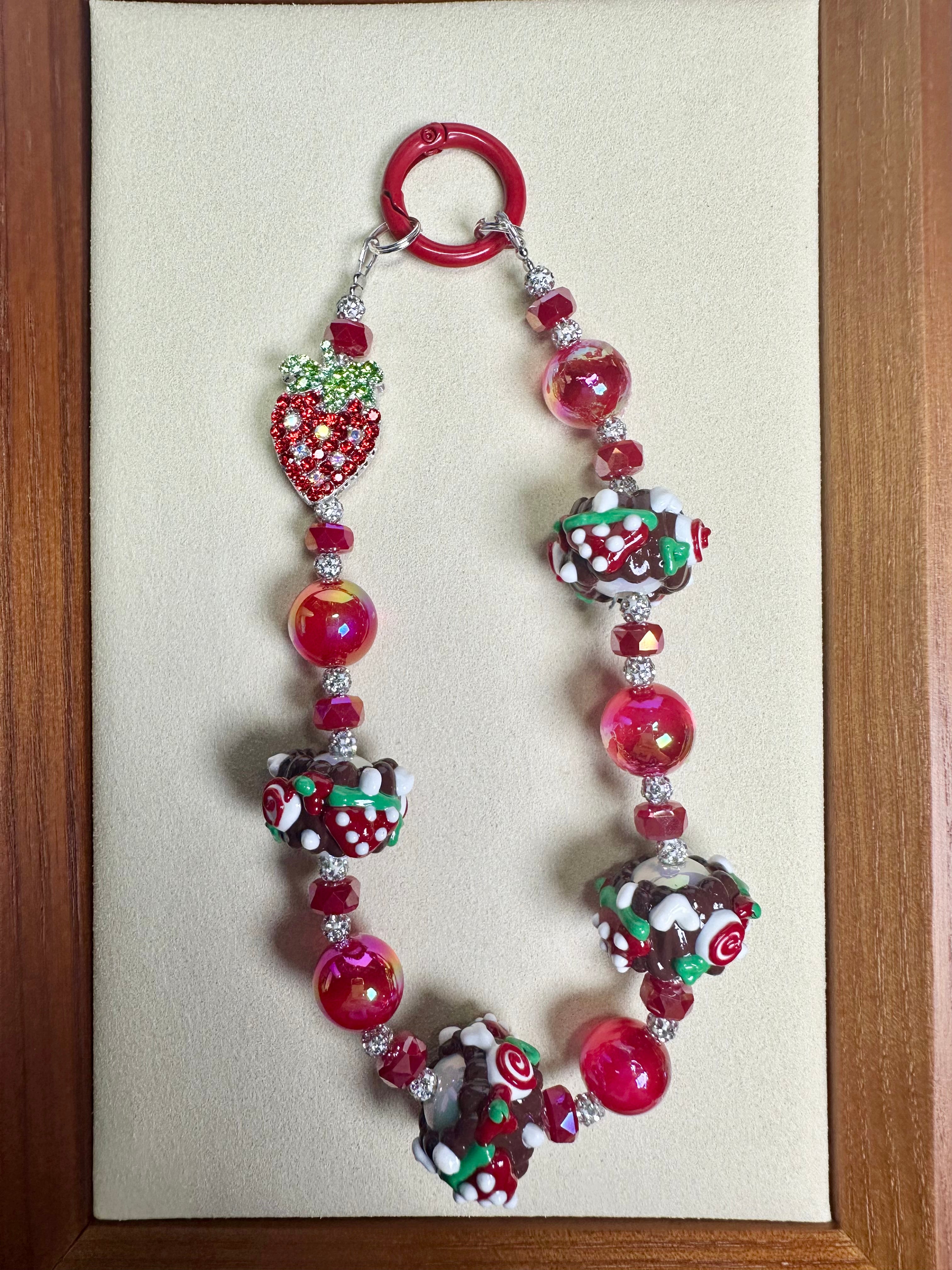 Decorative phone charm with colorful beads & strawberry on a beige background