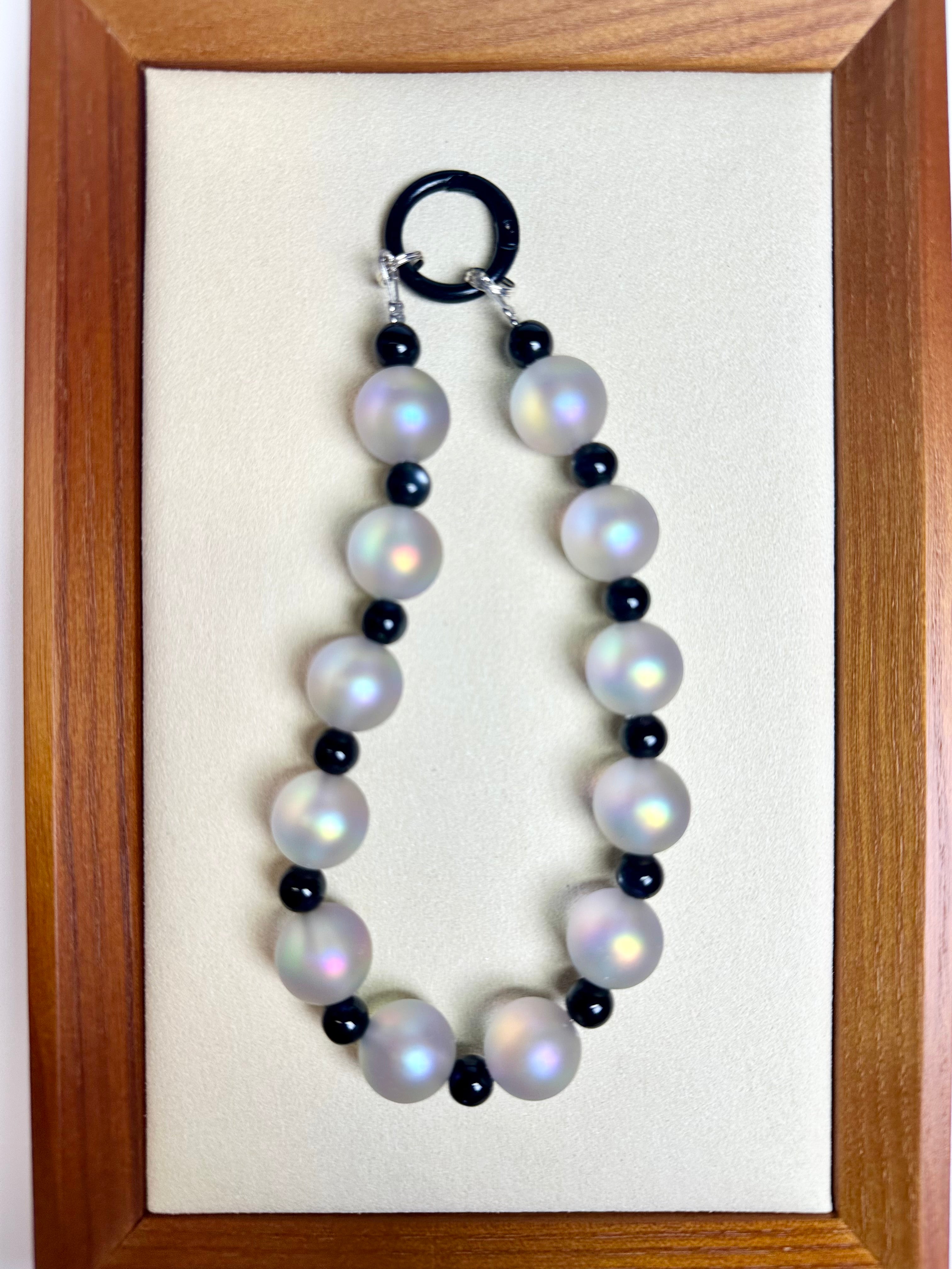 Phone charm with white and black beads on a wooden frame