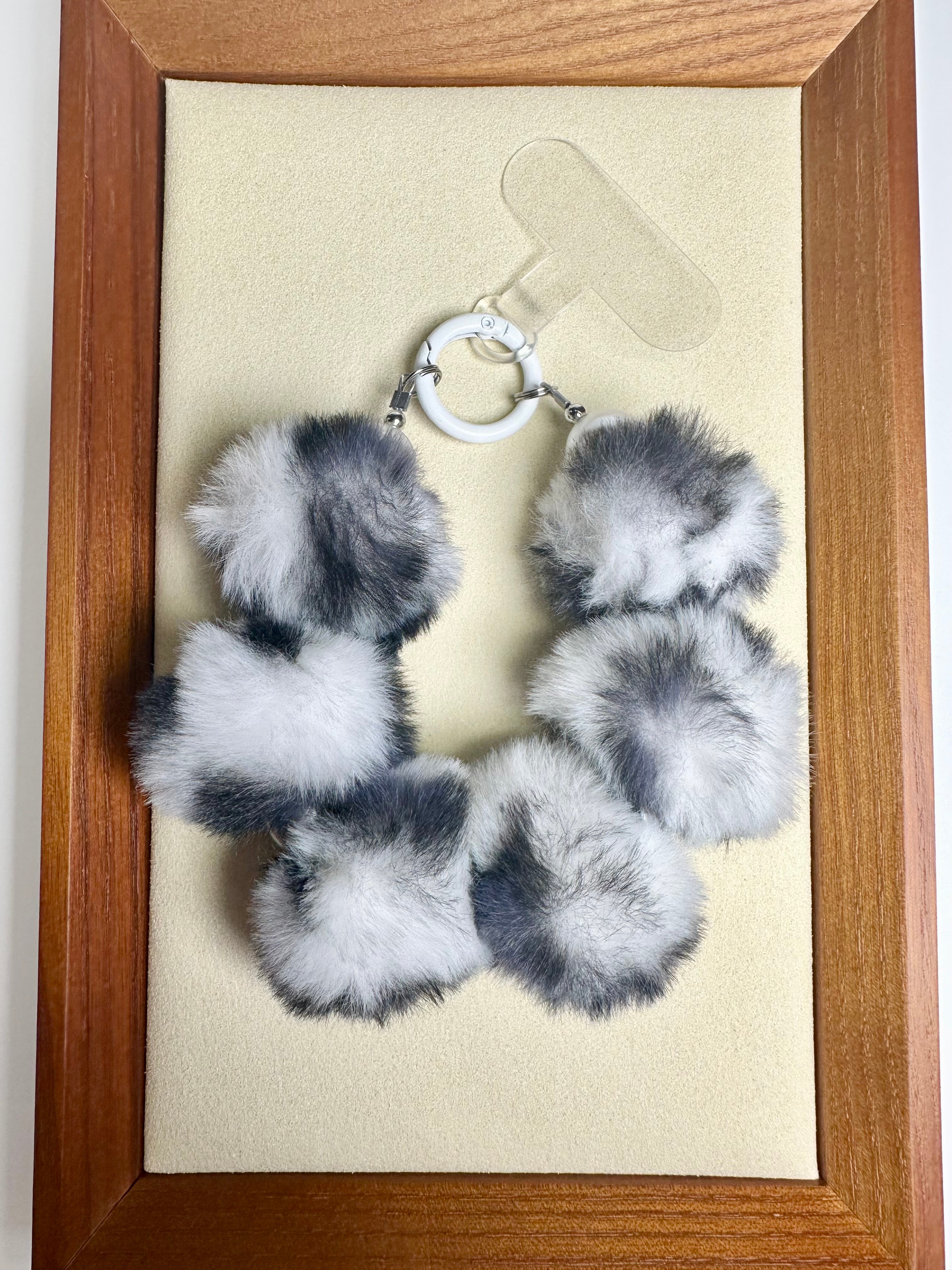 Fuzzy black & white phone charm with wooden frame and beige background